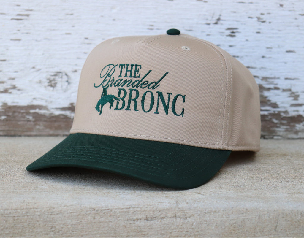 Beige and green cap with 'The Branded Bronc' text on a canvas hat.